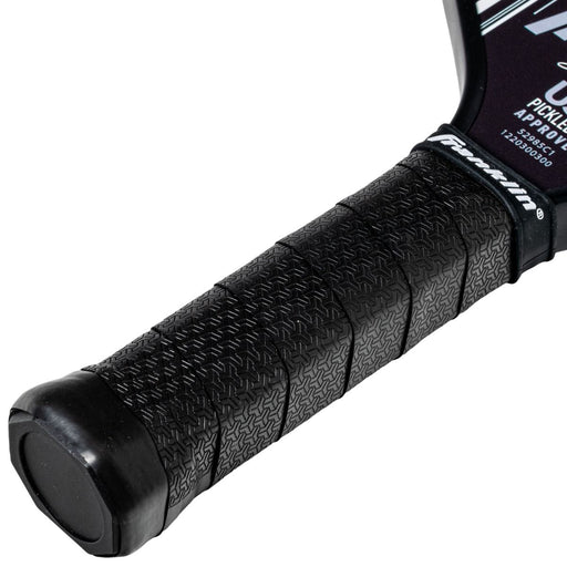 Close-up of a black pickleball paddle handle with a brand label on a white background