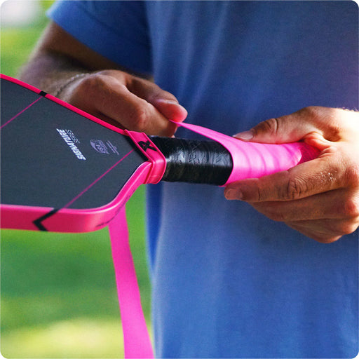 Person holding a pink and black paddle with a blurred background