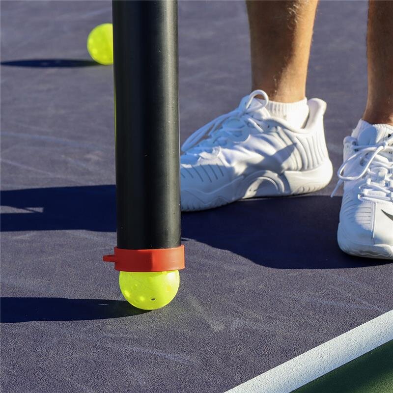 Tennis ball on a paddle with a person's feet in white shoes on a tennis court