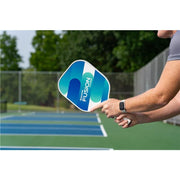 Person holding a pickleball paddle with 'Fusion' branding on a pickleball court.