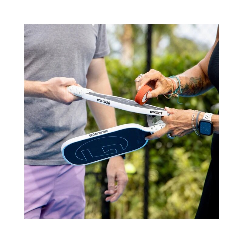 Person holding a white and blue insole with a brand logo, outdoors.