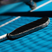 Tennis racket with decorative handle on a blue tennis court