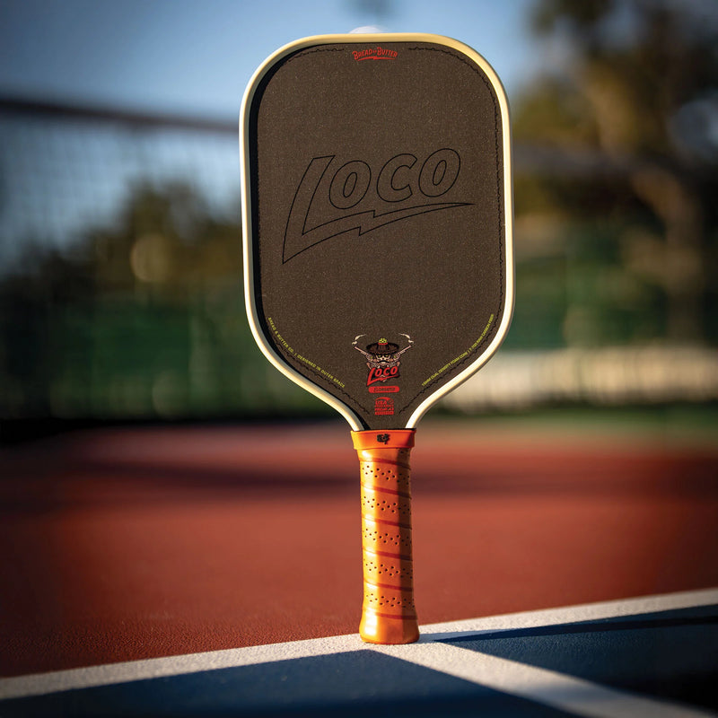 Pickleball paddle with 'Loco' branding on a tennis court