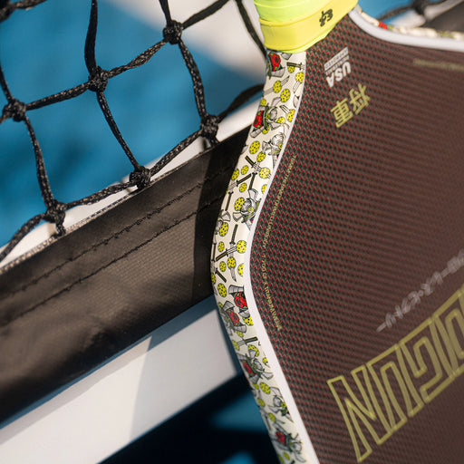Close-up of a tennis racket with a colorful handle against a blurred background