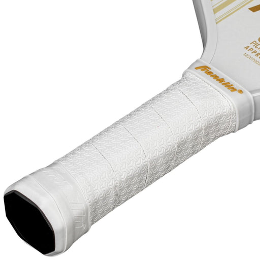 Close-up of a white tennis racket handle with textured grip and visible branding on a white background