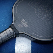 Close-up of a pickleball paddle with a blue background