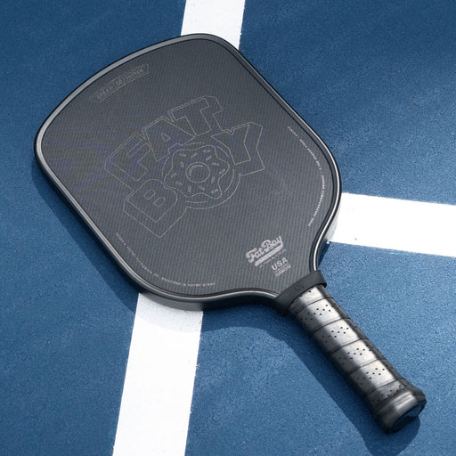 Black pickleball paddle on a blue court with white lines