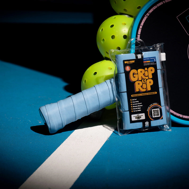 Blue pickleball grip with 'Grip It & Rip' packaging on a pickleball paddle against a dark background.