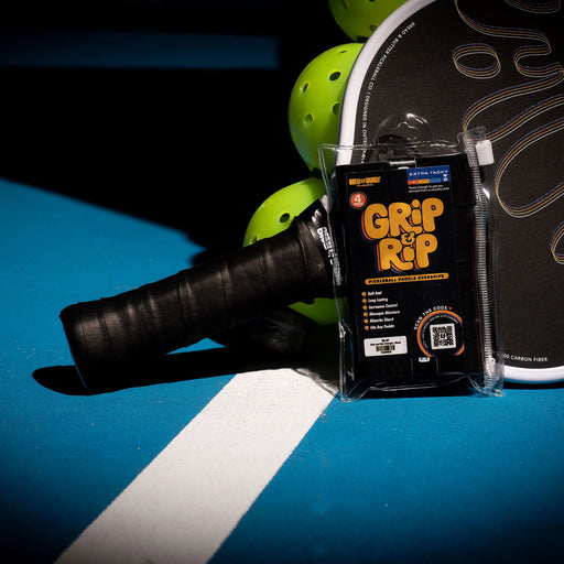 Grip and Rip tennis racket grip enhancer packaging on a tennis racket with balls in the background.