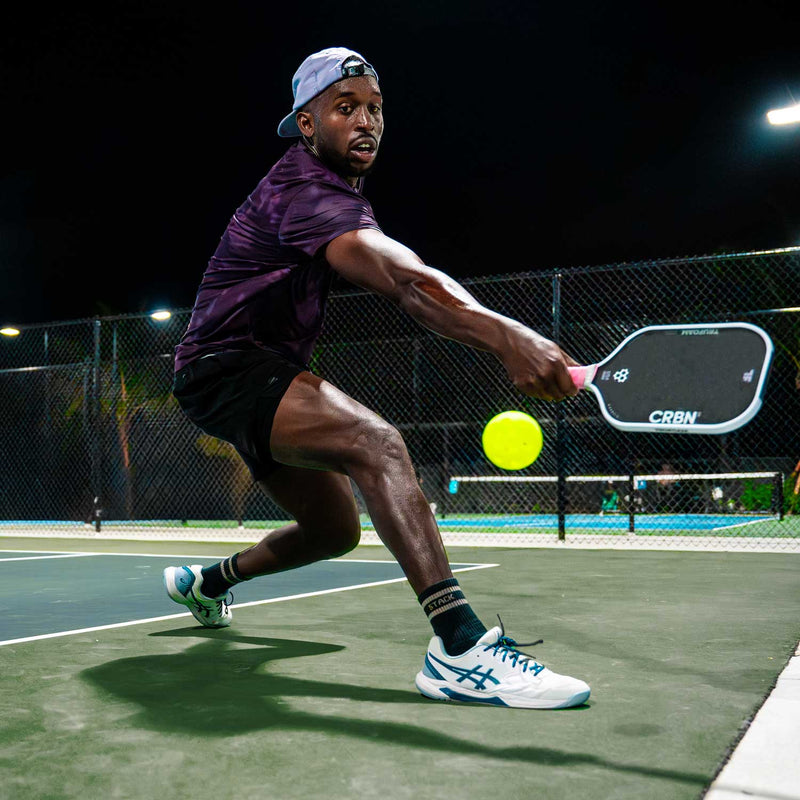 Person playing pickleball on an outdoor court at night