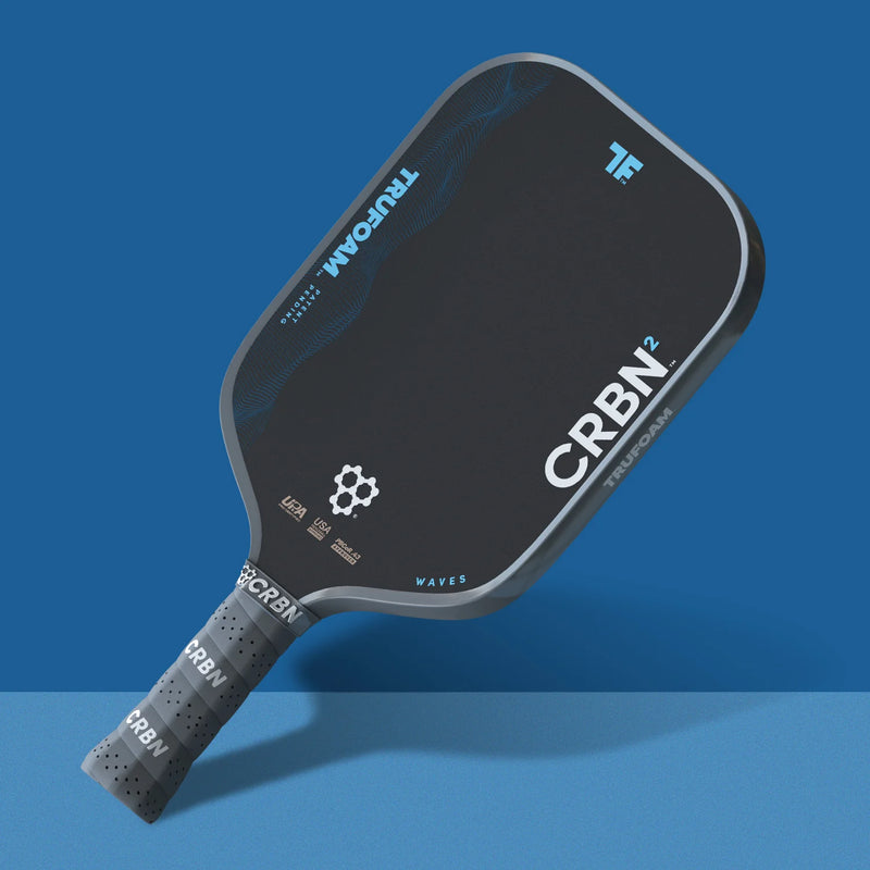 Black pickleball paddle with 'CRBN' branding on a blue background