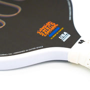 Close-up of a picklball paddle with branding on a white background