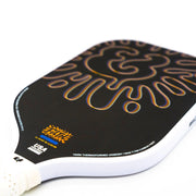 Close-up of a pickleball paddle with a black and gold design on a white background