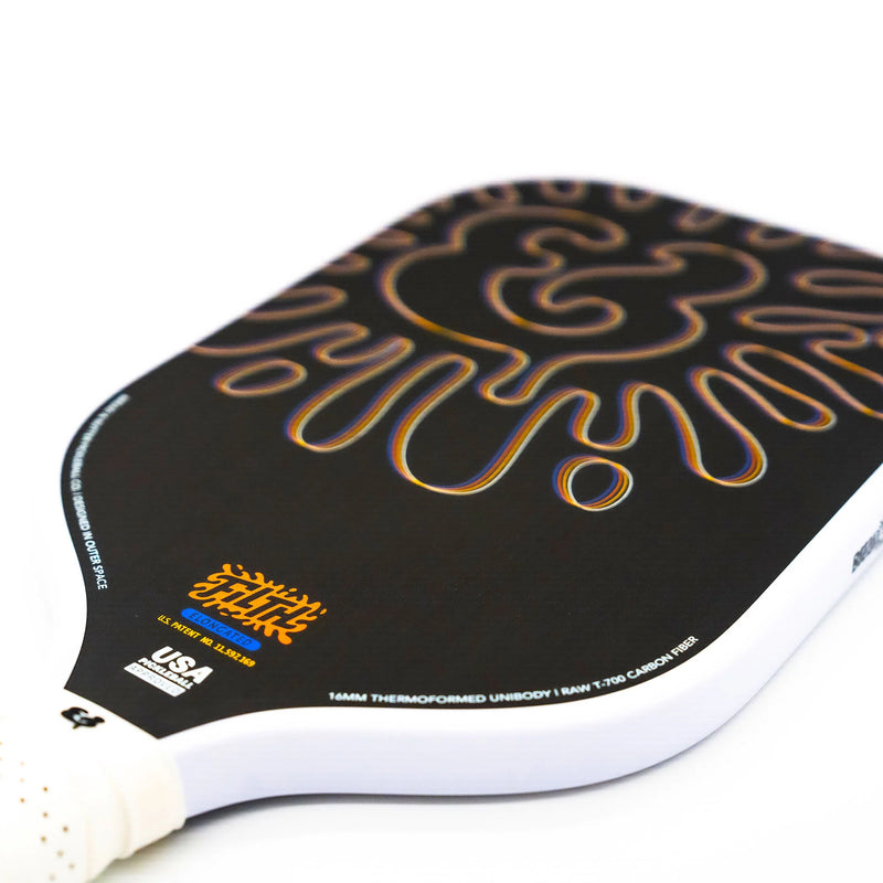 Close-up of a pickleball paddle with a black and gold design on a white background