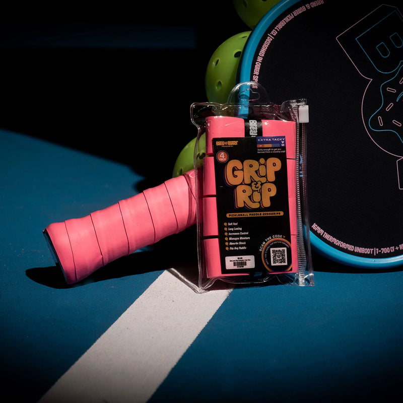 Pink tennis racket grip with 'Grip It' packaging on a blue surface