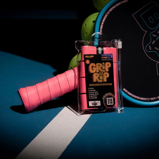 Pink tennis racket grip with 'Grip It' packaging on a blue surface