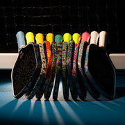 Colorful ping pong paddles arranged against a black net background
