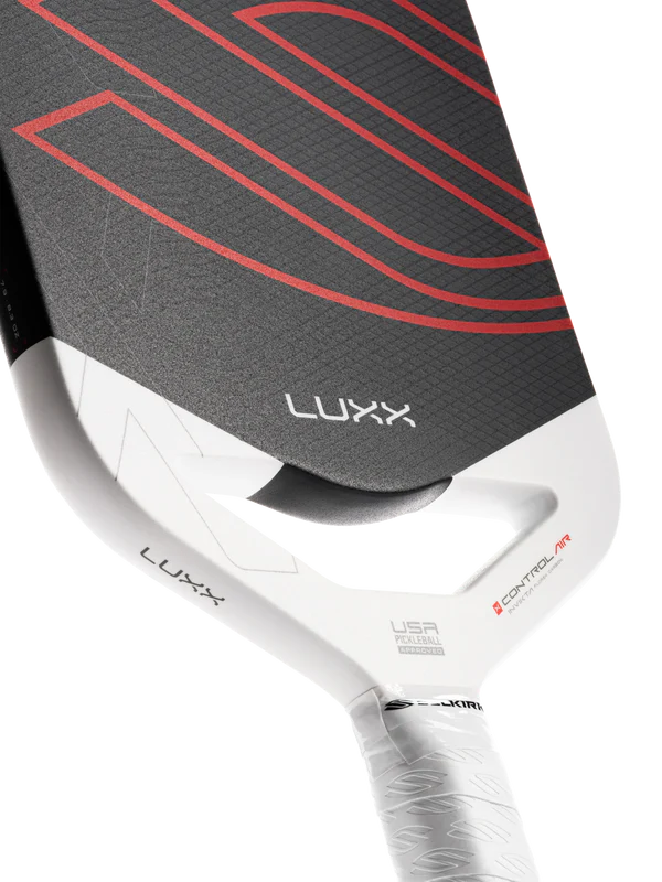 Close-up of a Luxx paddle with a white handle and black face with red accents on a white background.