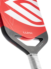 Close-up of a red and gray pickleball paddle with 'Luxx' branding on a white background