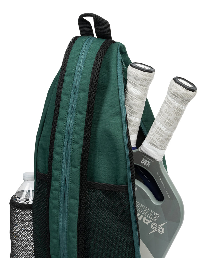 Green backpack with pickleball paddle and ball inside on a white background