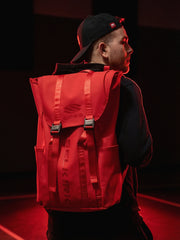 Person wearing a red backpack with a brand logo on a dark background